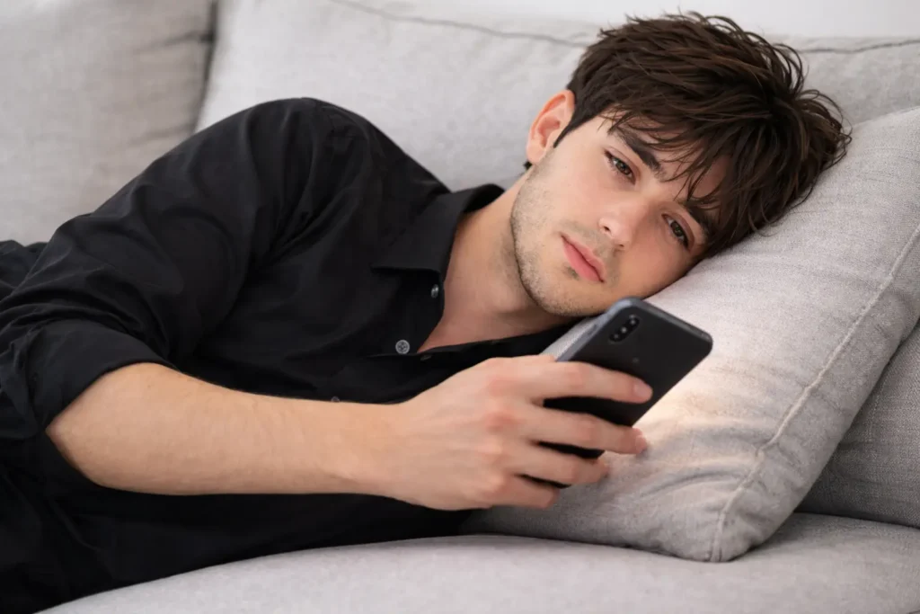 Selbstbewusstsein als Mann – unsicherer Mann schaut nachts auf sein SmartphoneVergleich und fehlendes Selbstbewusstsein